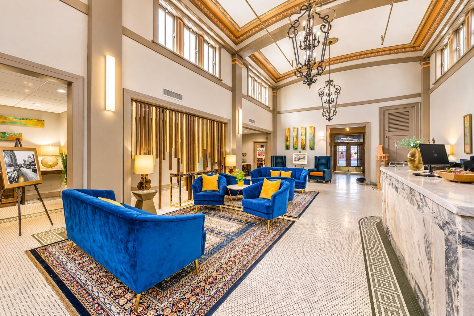 A spacious lobby with high ceilings, a chandelier, and a reception desk.