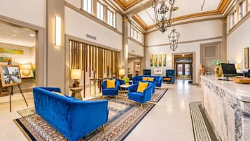 A spacious lobby with high ceilings, a chandelier, and a reception desk.