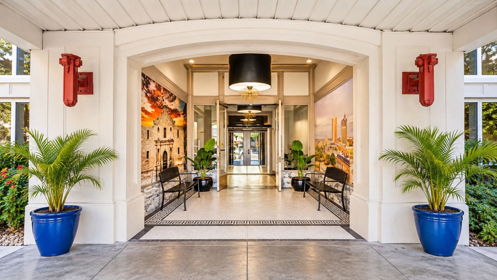 Entrada de hotel con un gran arco, plantas en macetas y vista al vestíbulo.