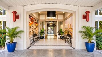 Entrada de hotel con un gran arco, plantas en macetas y vista al vestíbulo.