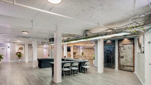 Een ruime, moderne kantoorruimte met hoge plafonds, zichtbare ventilatiekanalen en een combinatie van daglicht en kunstlicht.