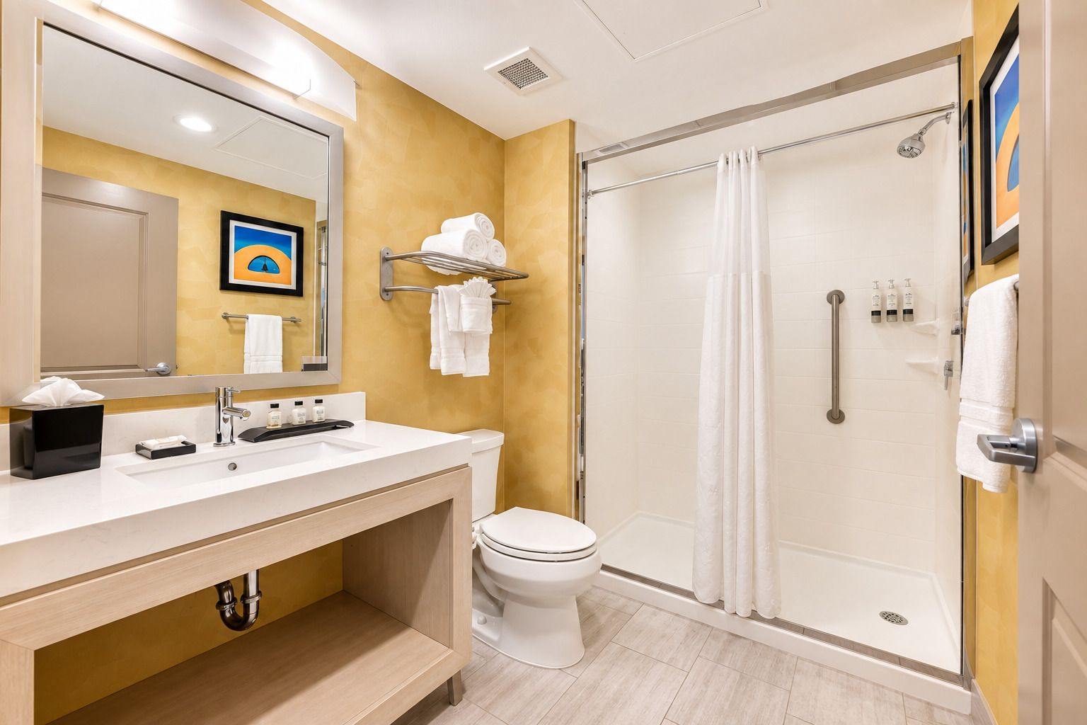 Un baño moderno con un lavamanos blanco, un inodoro y una ducha con mampara de vidrio.
