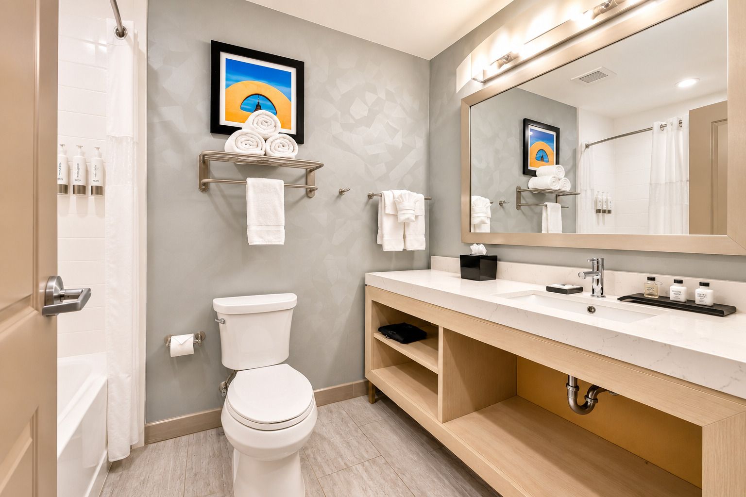 A modern bathroom with a toilet, sink, and mirror. There are towels and toiletries on the counter.