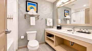 A modern bathroom with a toilet, sink, and mirror. There are towels and toiletries on the counter.