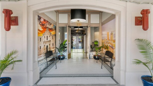 Een hotel lobby met een modern ontwerp, met een grote muurschildering, zitgedeeltes en een centrale kroonluchter.