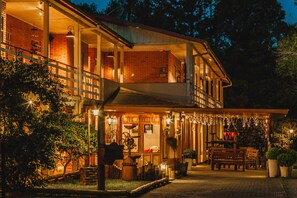 A two-story building with a balcony and outdoor seating area, surrounded by trees. - Pousada Betânia (Gramado)