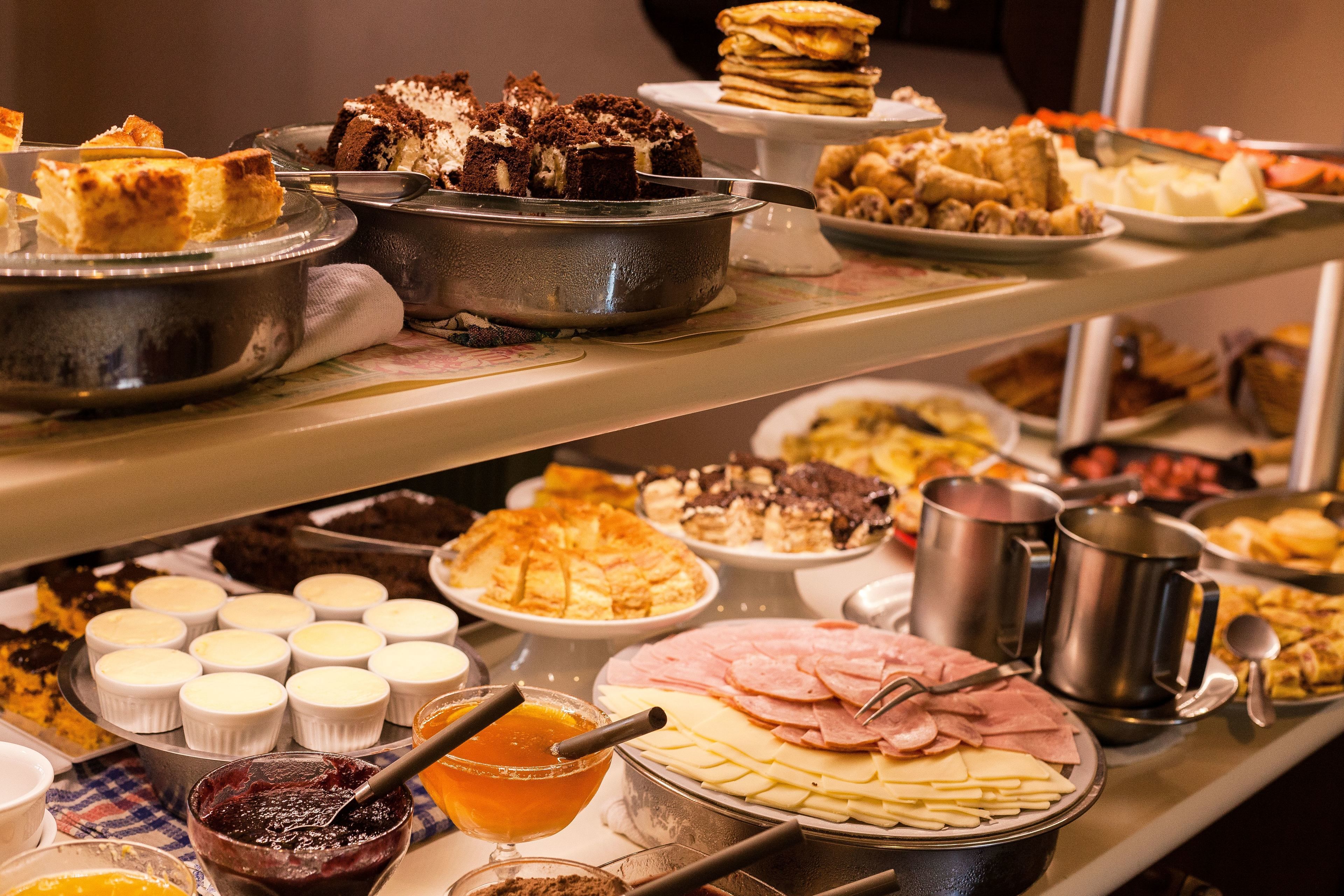 A buffet with various food items including cakes, pastries, and a variety of cheeses and meats.