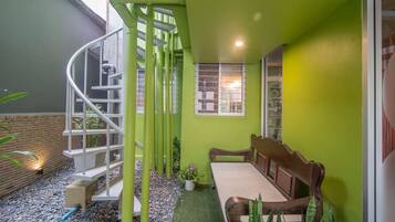 A small, enclosed outdoor space with a spiral staircase, a wooden bench, and a small table.