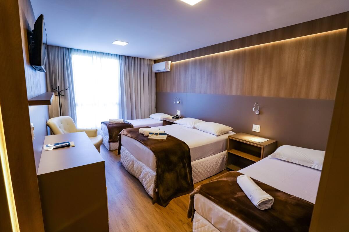 Une chambre d’hôtel avec deux lits, un bureau, une chaise et une télévision.