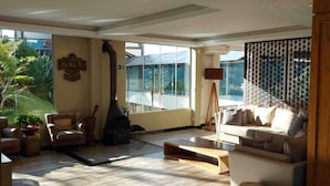 A spacious living room with a fireplace, comfortable seating, and large windows offering a view of the outdoors. - Sky Valle Hotel (Gramado)