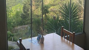 A dining area with a table and chairs, large windows offering a view of a lush landscape. - Sky Valle Hotel (Gramado)