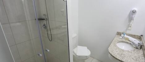 Un baño con ducha envuelta en vidrio, un inodoro y un lavamanos con encimera de granito.
