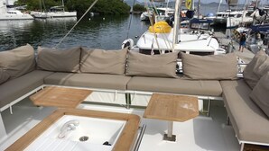 Un bote con interior blanco, cojines color beige y una mesa de madera.