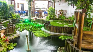 Ein ruhiger Innenbereich mit Garten, Teich, Holzzäunen und Sitzbereichen.
