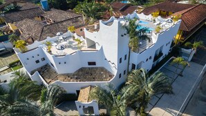 Ein weißes Gebäude mit einem markanten architektonischen Design, das mehrere Balkone und einen Swimmingpool aufweist.