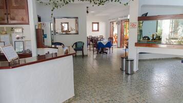 Un área de recepción con mostrador, sillas, una zona de comedor con mesas y un acuario.