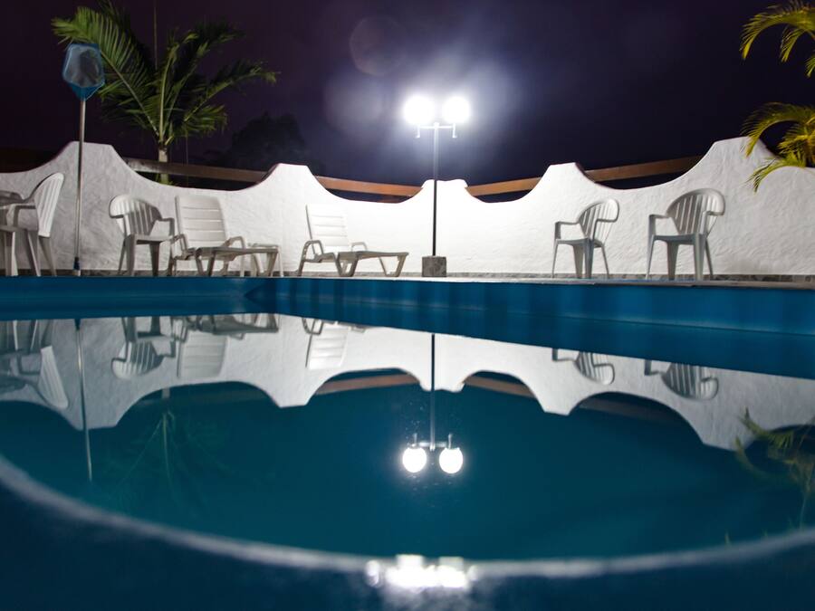 Une piscine avec des chaises blanches et un lampadaire.