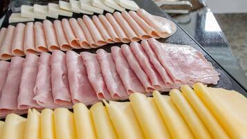 Mesa de buffet com diversos alimentos, incluindo carnes, queijos e doces.