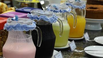 Un bufé con diversas bebidas en jarras, algunas con adornos azules con flecos en las tapas.