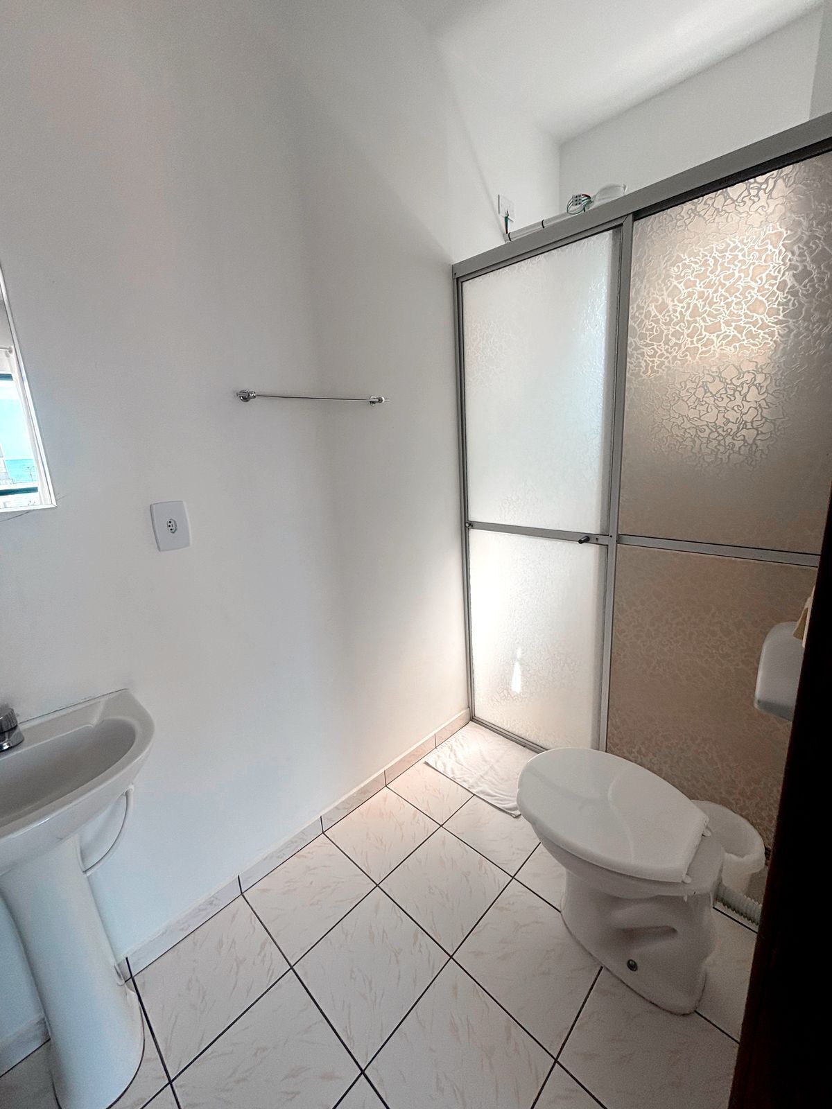 Une salle de bain équipée de toilettes, d’un lavabo et d’une douche avec des portes en verre dépoli.