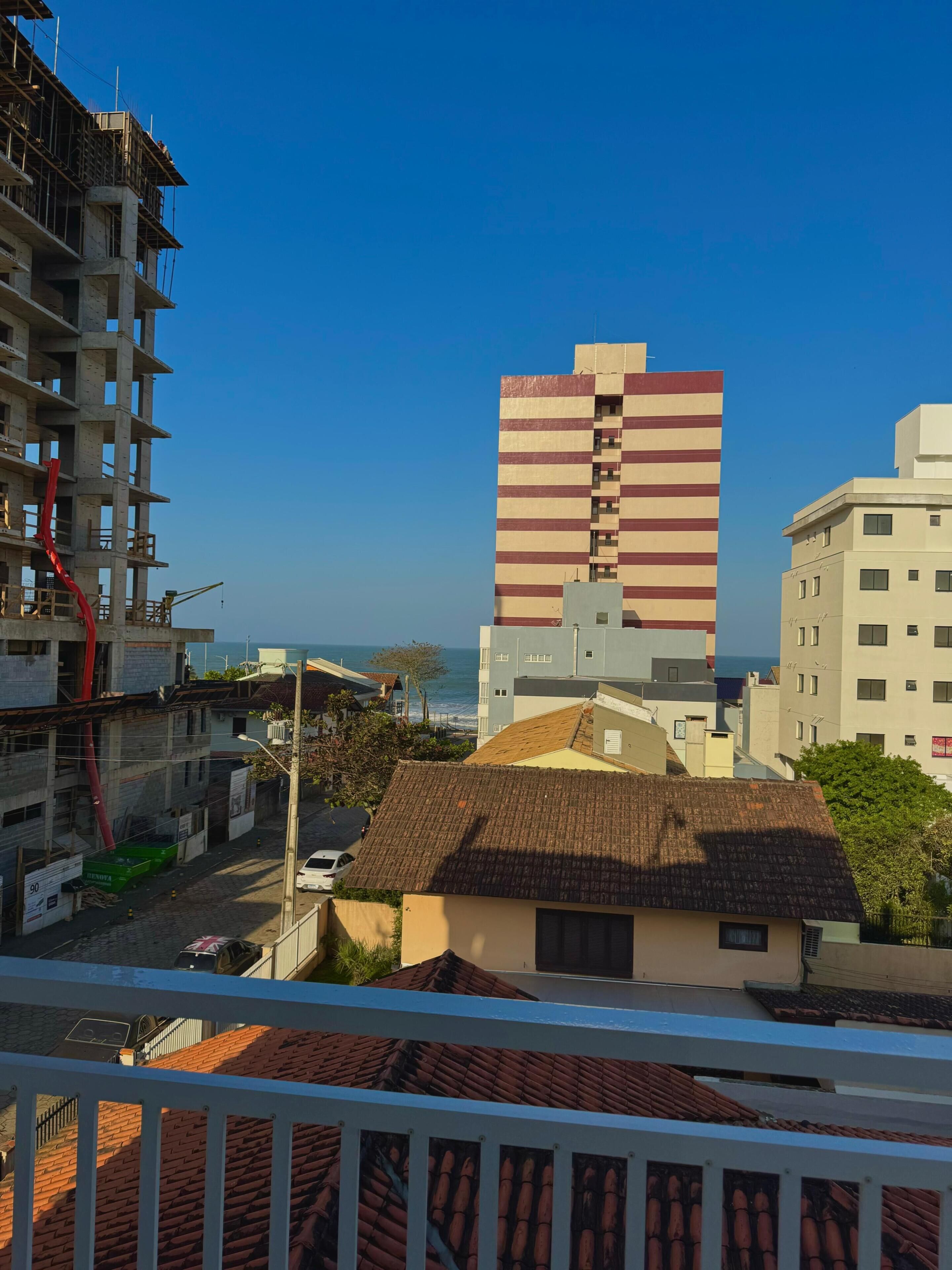 A coastal cityscape with a prominent striped building, a construction site, and a view of the sea.