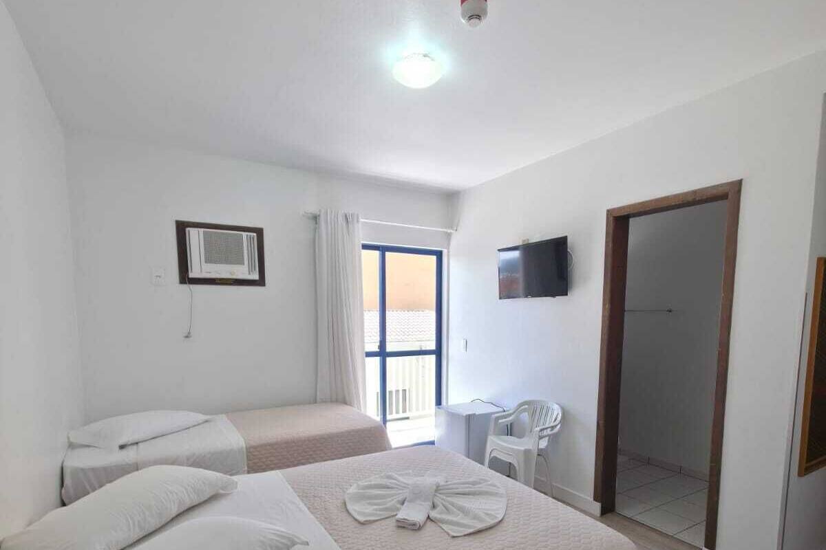 A hotel room with two beds, a TV, a mirror, and a balcony.