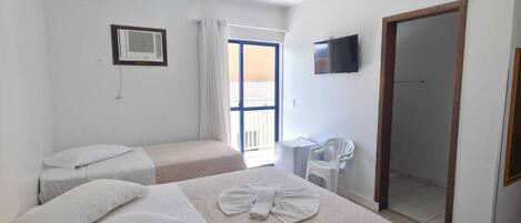 A hotel room with two beds, a TV, a mirror, and a balcony.