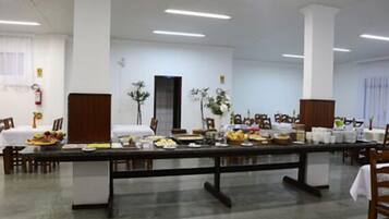 A conference room with a long table set for a meal, white walls, and a ceiling with fluorescent lights.
