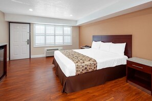 Ein Hotelzimmer mit einem großen Bett, einem Schreibtisch, einem Stuhl, einem Heizkörper und einer Tür.