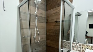 A modern bathroom with a glass-enclosed shower, a toilet, and a sink with a decorative tile backsplash. - Pousada Campo Verde (São João del Rei)