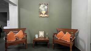 A room with two wooden benches, a small table, a framed picture on the wall, and a chandelier. - Pousada Campo Verde (São João del Rei)