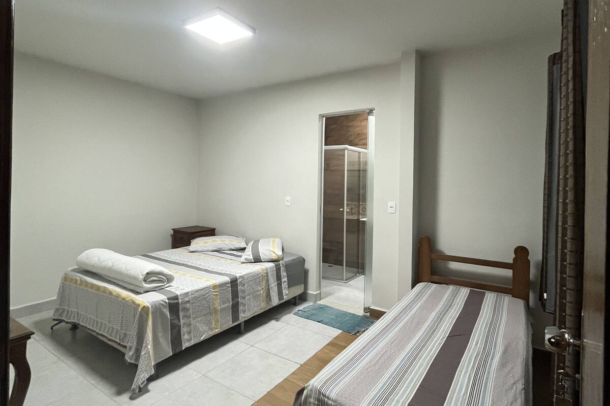 Une chambre avec deux lits, un plancher en bois et une cabine de douche en verre.