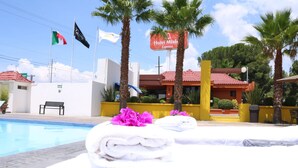 A hotel pool area with towels and flowers, flags, and a sign for Hotel Misic Express. - Hotel Misión Express Saltillo (Saltillo)
