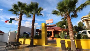 A hotel entrance with palm trees, a yellow wall, and a sign for Hotel Misión. - Hotel Misión Express Saltillo (Saltillo)
