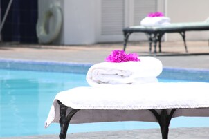Zona de piscina con una mesa cubierta con una toalla blanca y una flor rosa.