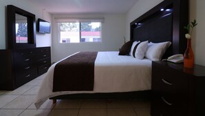 A bedroom with a bed, a dresser, a mirror, a TV, and a window. - Hotel Misión Express Saltillo (Saltillo)