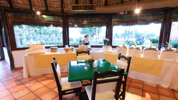 A dining area with tables set for service, a view of the outdoors, and a thatched roof ceiling. - Hotel Misión Express Saltillo (Saltillo)