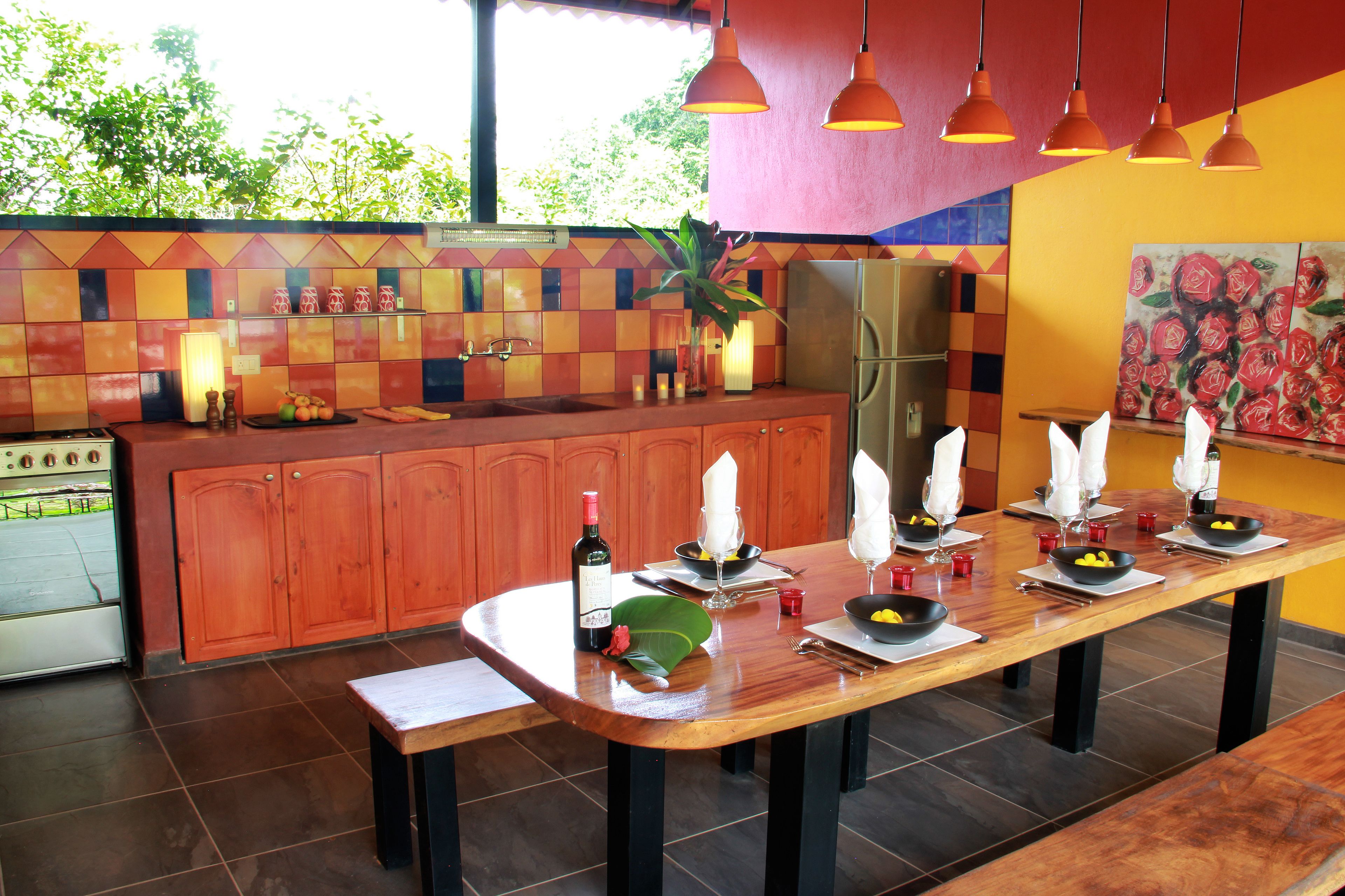 A kitchen with a wooden table set for dining, a refrigerator, and a tiled backsplash.