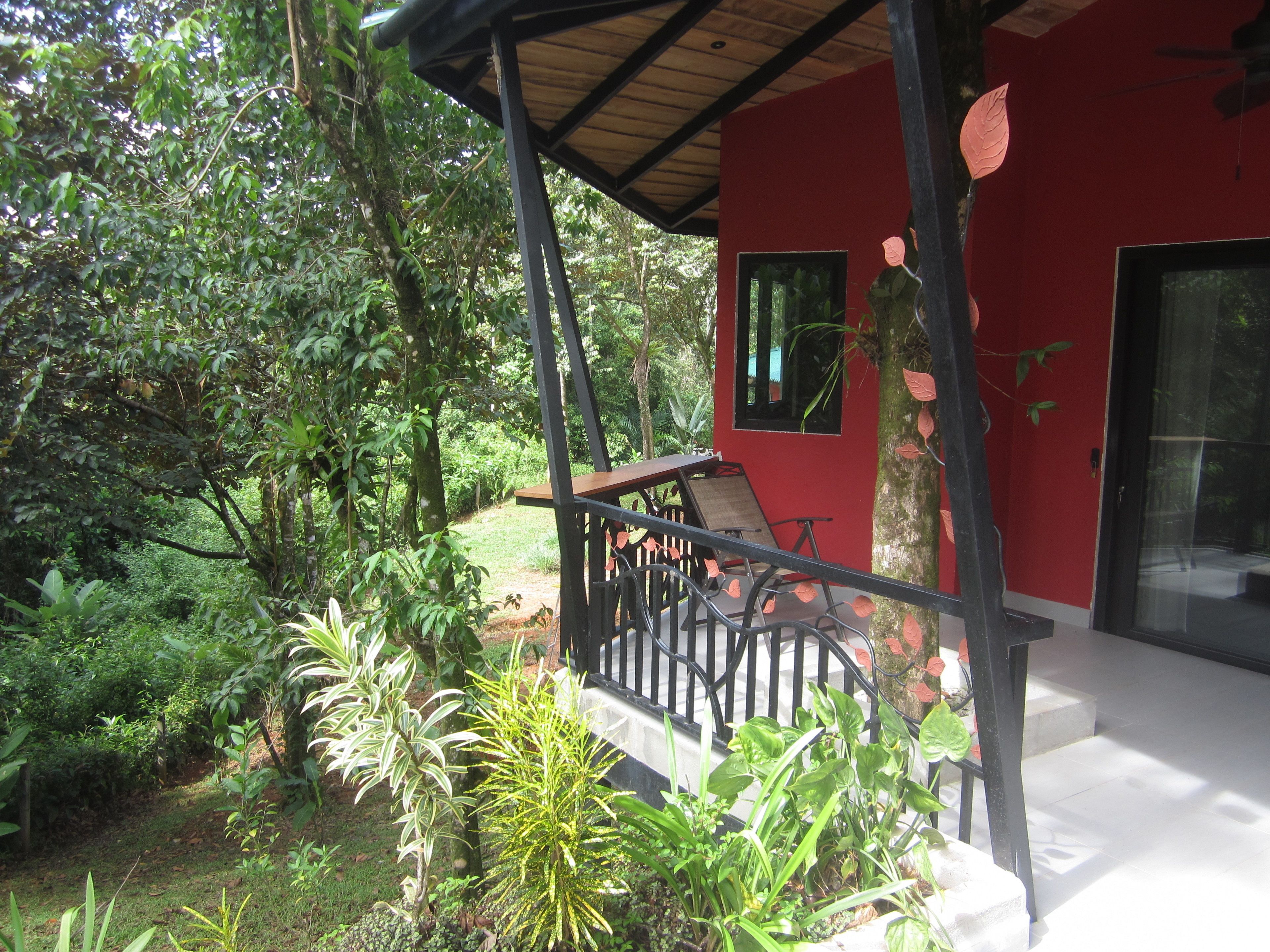 Ein rotes Gebäude mit einer Veranda und einem Garten.