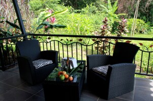 A balcony with wicker furniture and a table with fruits and a bottle.