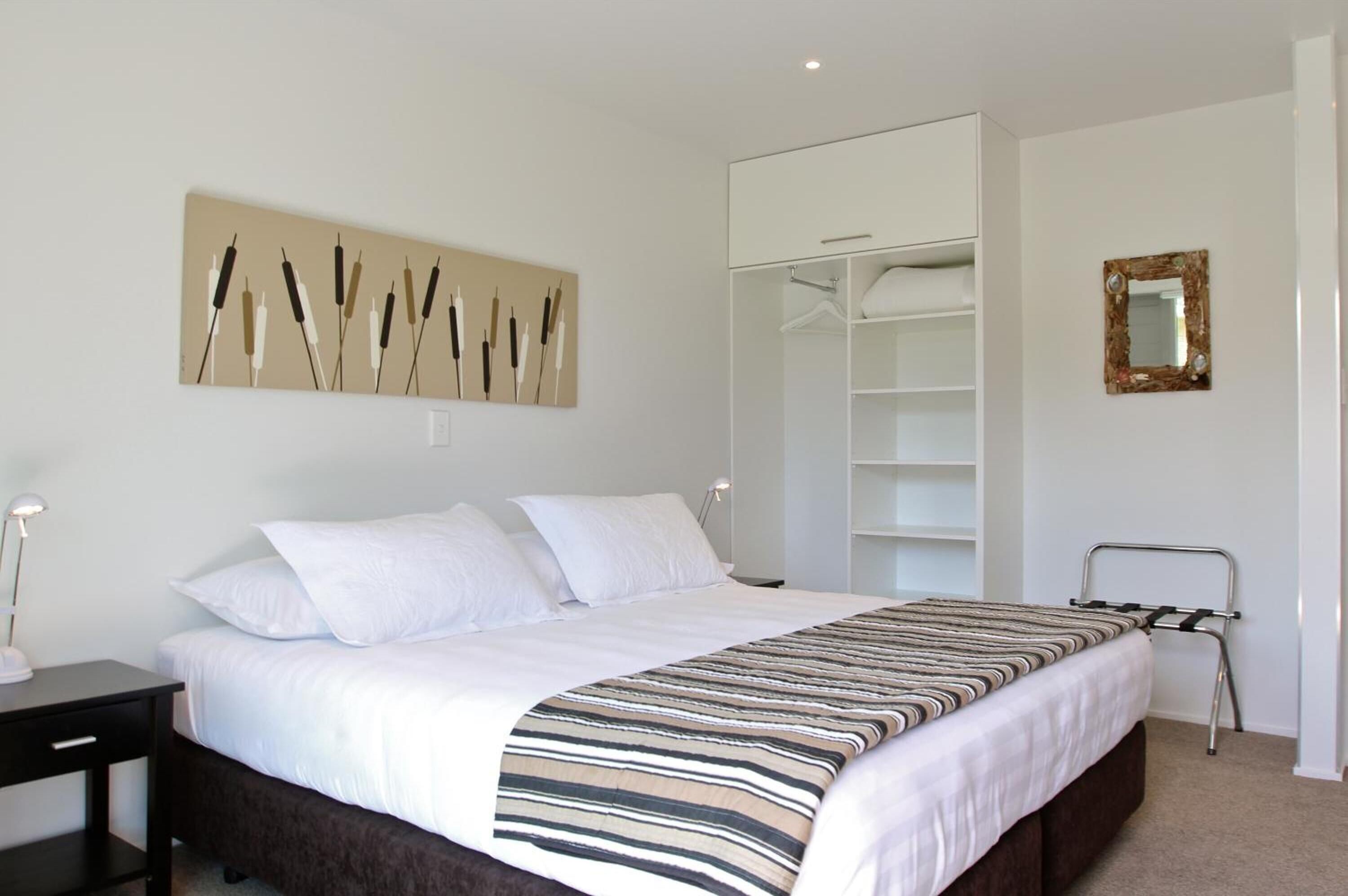 A bedroom with a bed, a bedside table, a wardrobe, and a mirror.