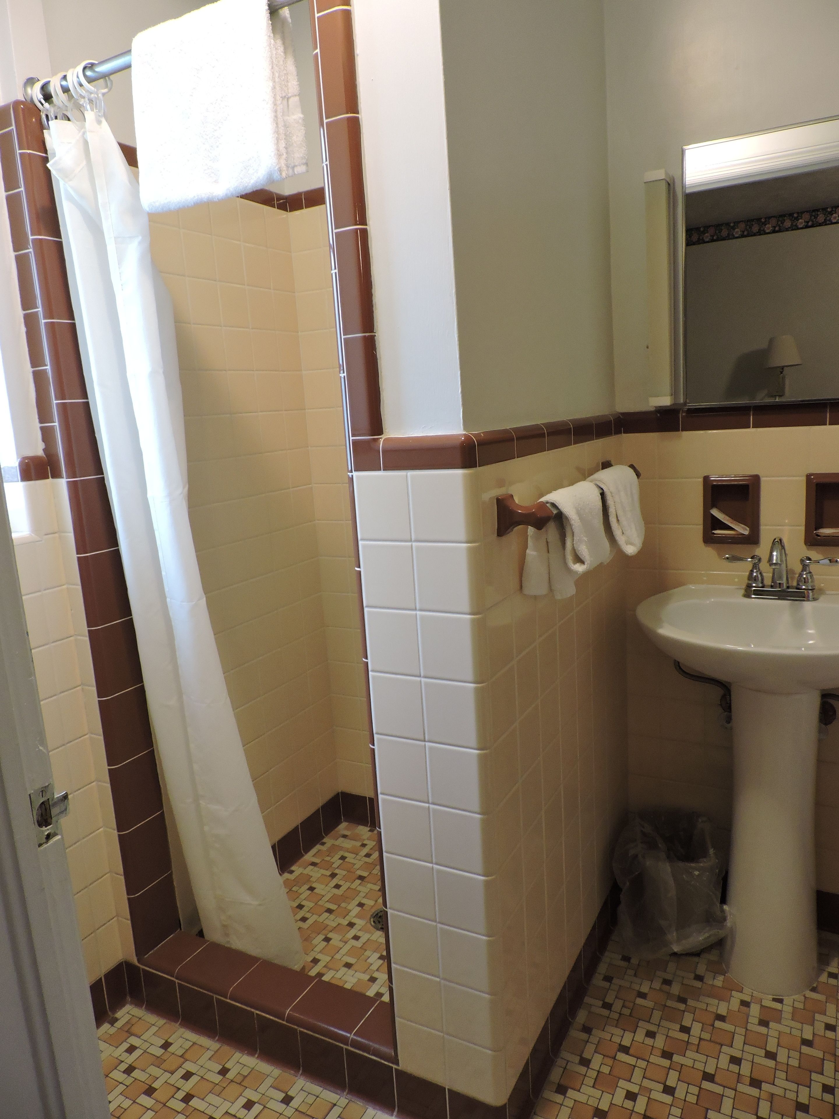 Un baño con ducha, lavamanos y espejo.