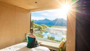 A room with a large window overlooking a river and mountains. - EcoScapes (Kinloch)