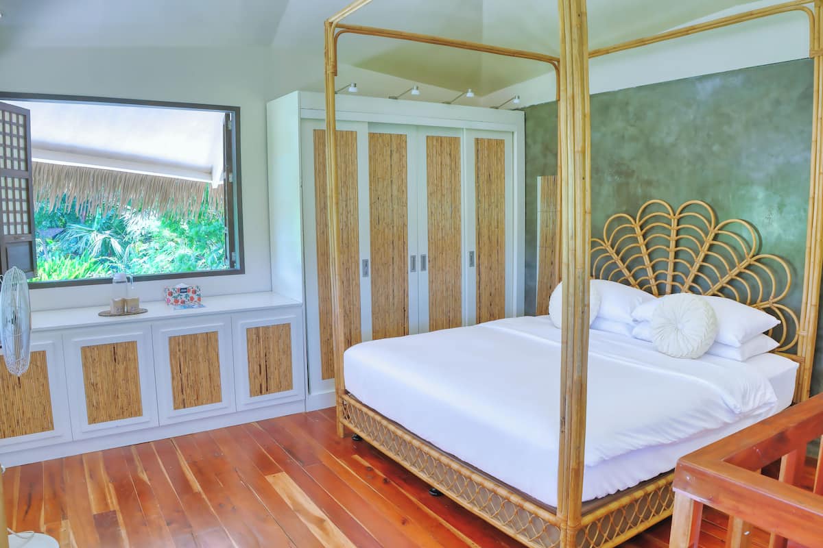Un dormitorio con una cama con dosel, un ventanal con vistas a zonas verdes y un armario empotrado con paneles de madera.