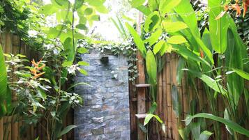 Een stenen muur met een houten omheining en weelderige groene beplanting.