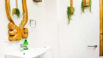 A bathroom with a white sink, a white toilet, a large mirror, and two wall-mounted planters with green plants.