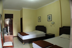 A hotel room with two beds, a desk with a chair, a telephone, and a television. - Ananda Hotel (Yogyakarta)