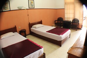 A hotel room with two single beds, a small table, two chairs, and a desk. - Ananda Hotel (Yogyakarta)