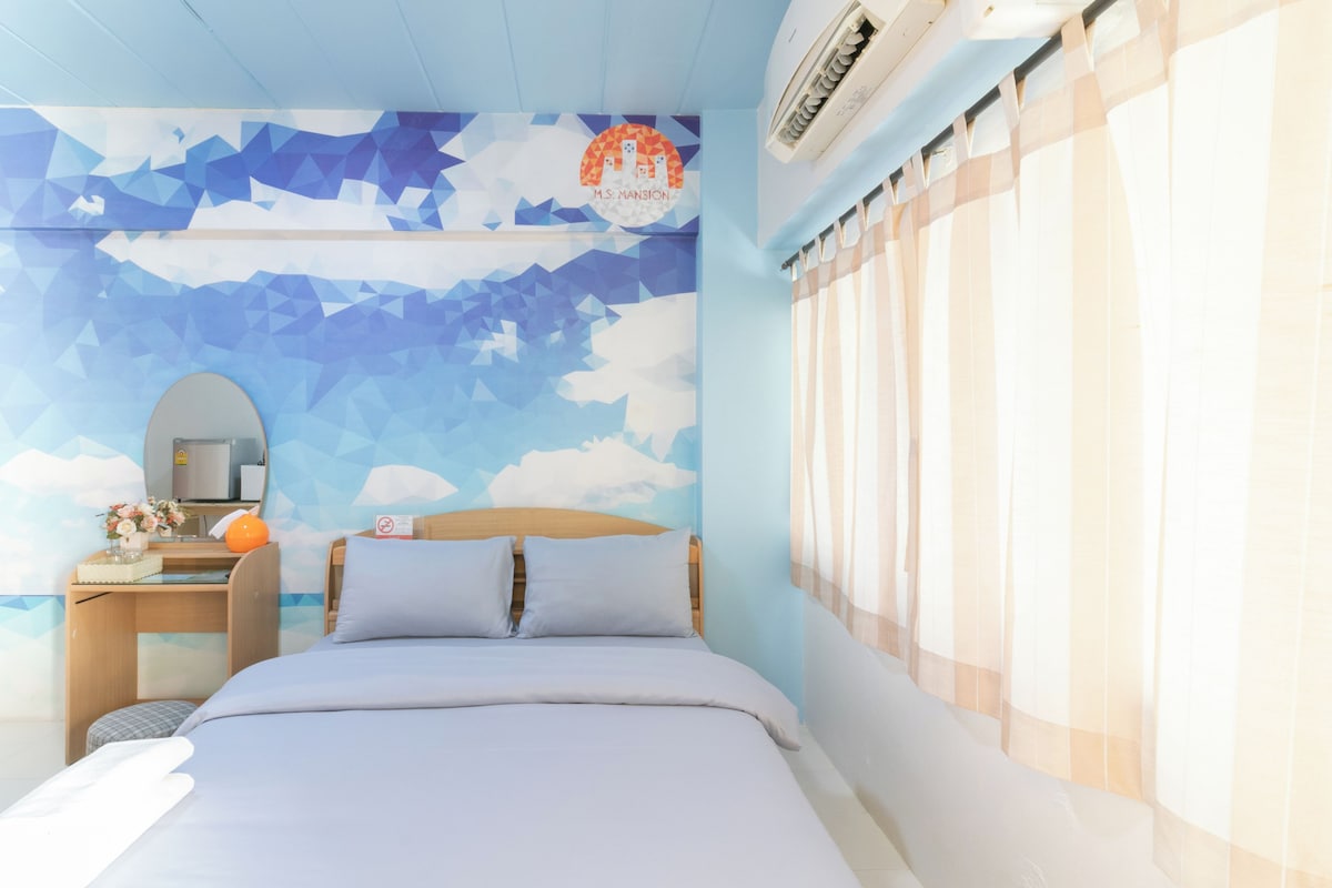 A bedroom with a bed, a nightstand, a mirror, and a wall with a geometric pattern.