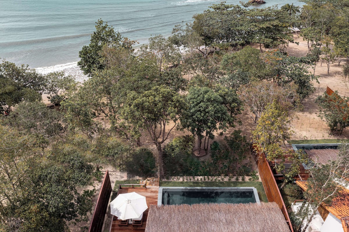 Propiedad frente a la playa con piscina, terraza de madera y vista al océano.